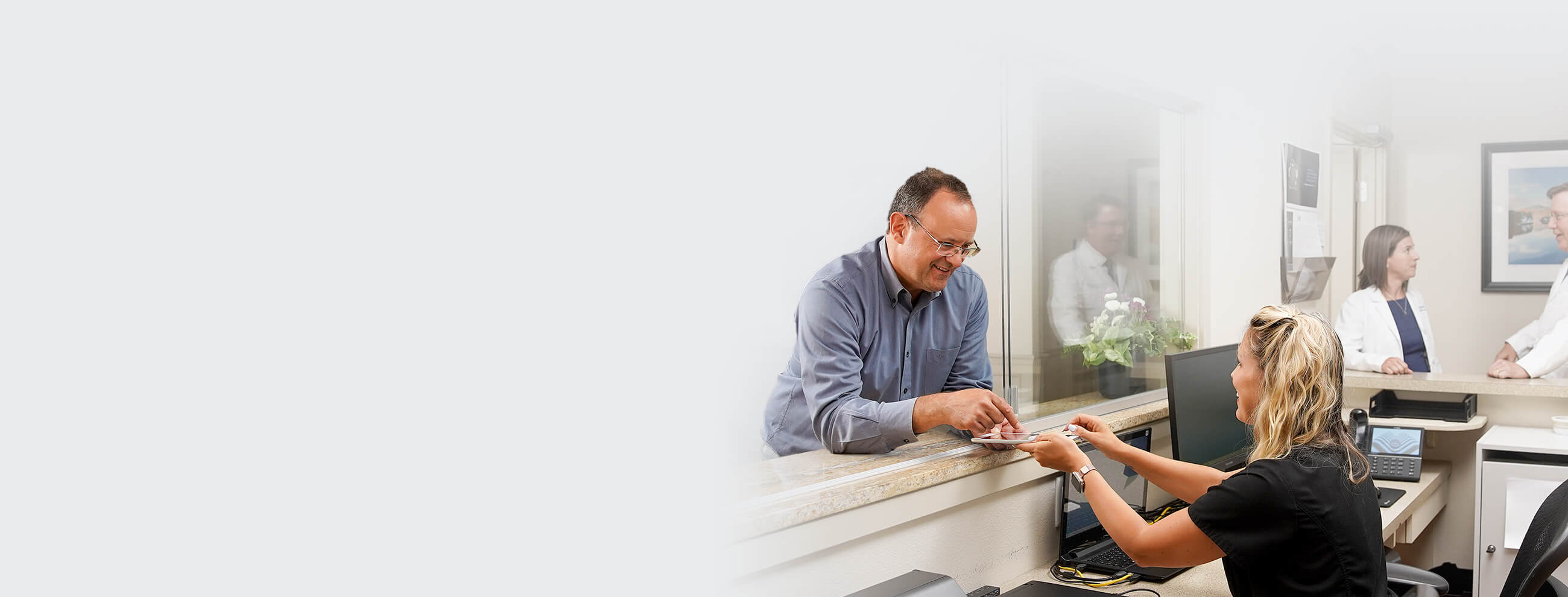 A patient talking with the team member at front desk